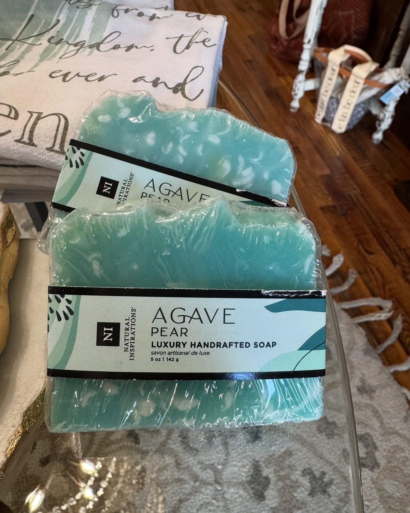 Three wrapped bars of blue-green agave pear soap stacked on a table.