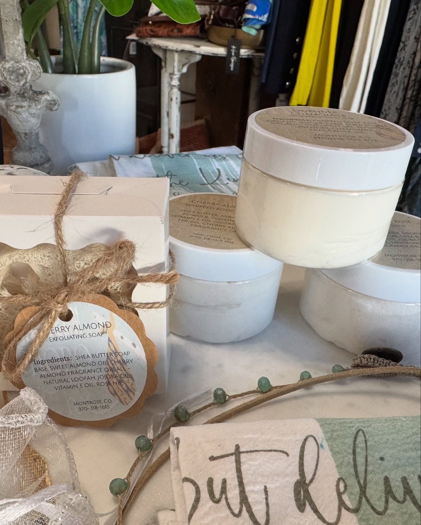 Jars of cream stacked on a display with a tag and a plant in the background.