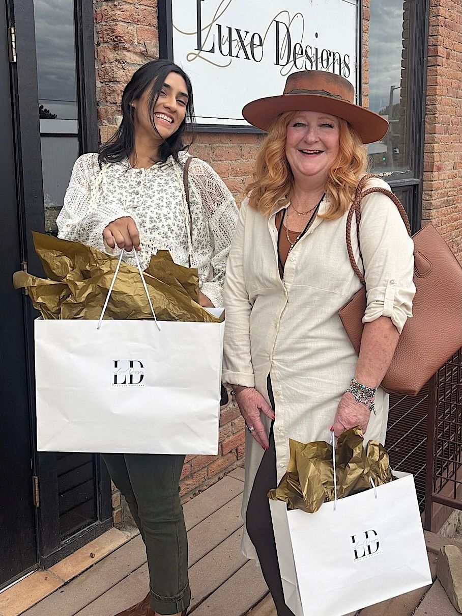 Two women outside a store, holding shopping bags with 