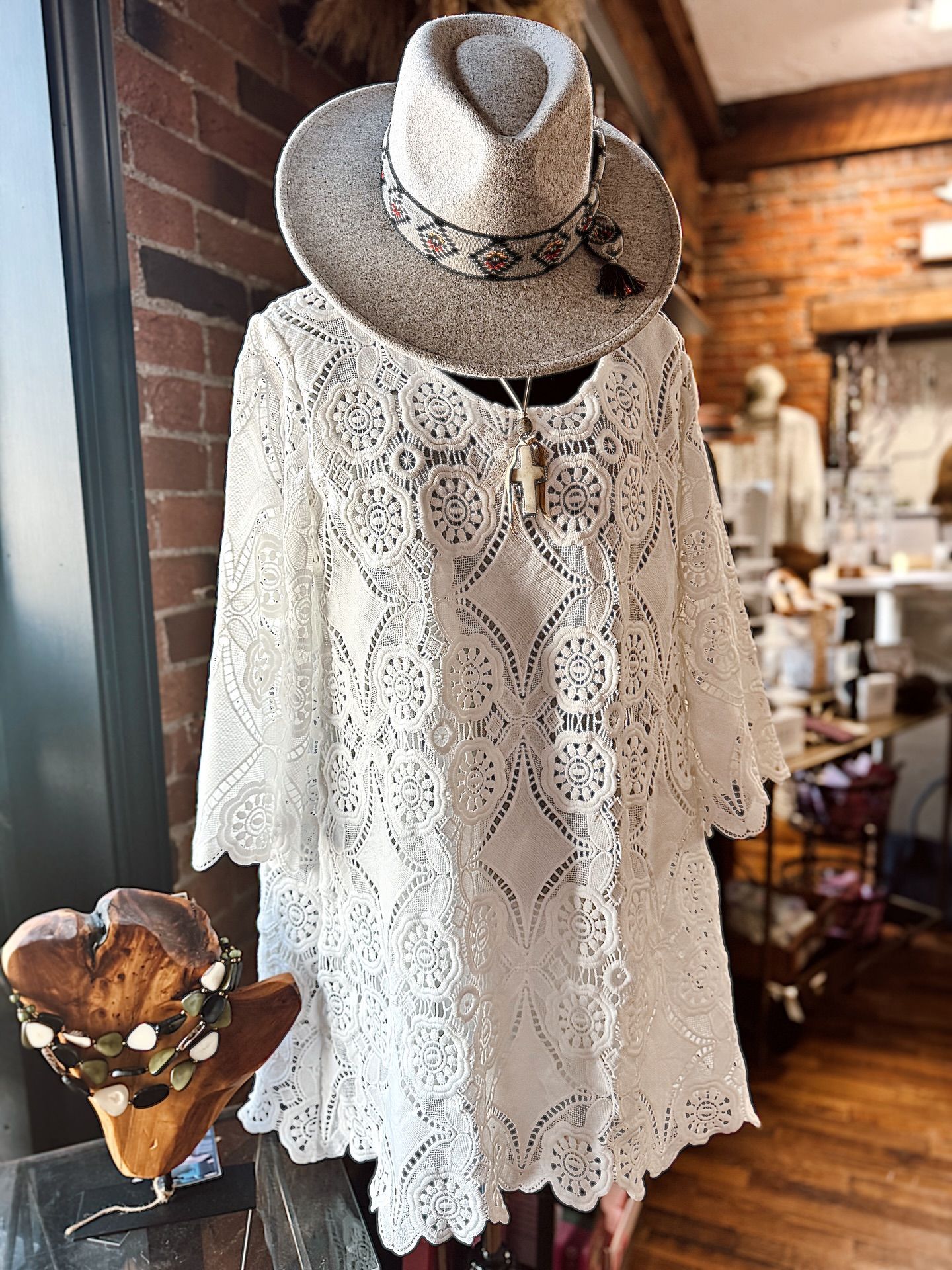 White lace dress and straw hat on a mannequin in a shop.