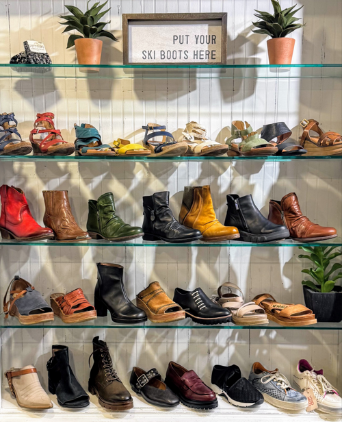 Shoes displayed on shelves with a sign reading