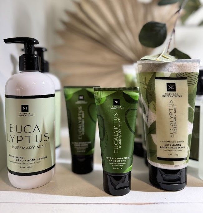 Bottles and tubes of Eucalyptus Rosemary Mint hand care products on a white shelf.