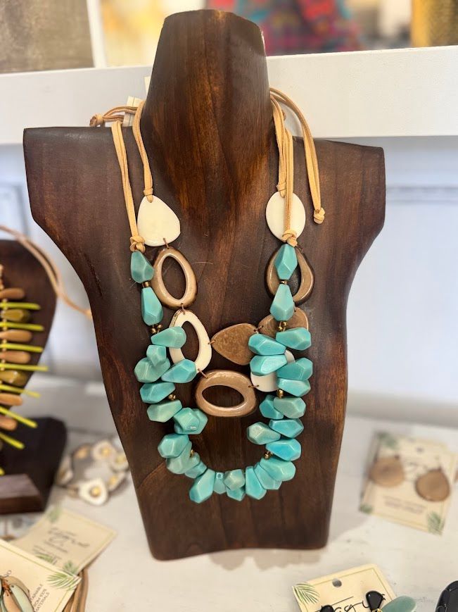 Turquoise and wood statement necklace on a wooden display stand.
