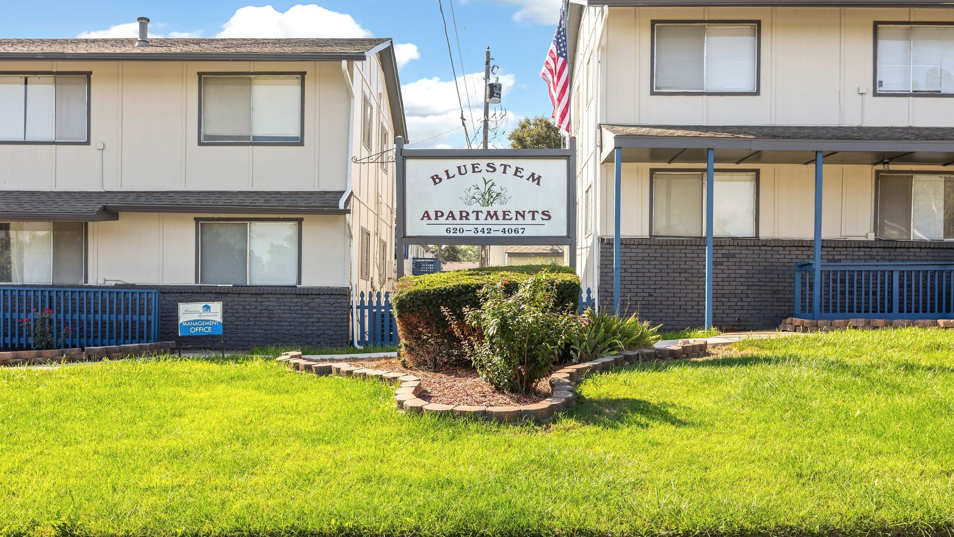 Two-story beige apartment buildings with blue trim, a sign for 