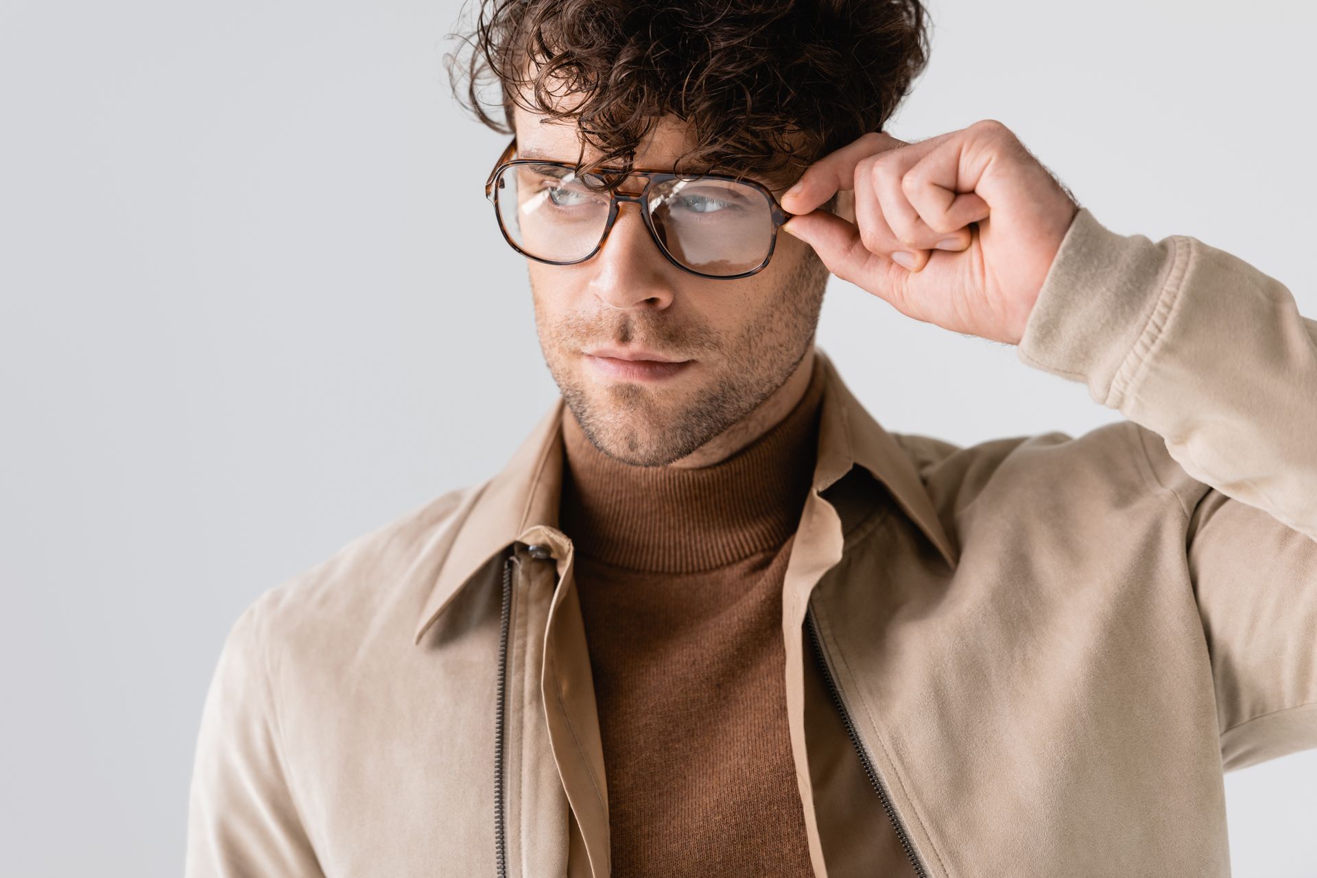 Ein Mann mit Brille und hellbrauner Jacke rückt seine Brille zurecht.