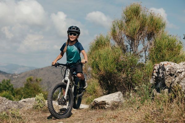 Ein kleiner Junge fährt mit dem Fahrrad auf einem Pfad in den Bergen.