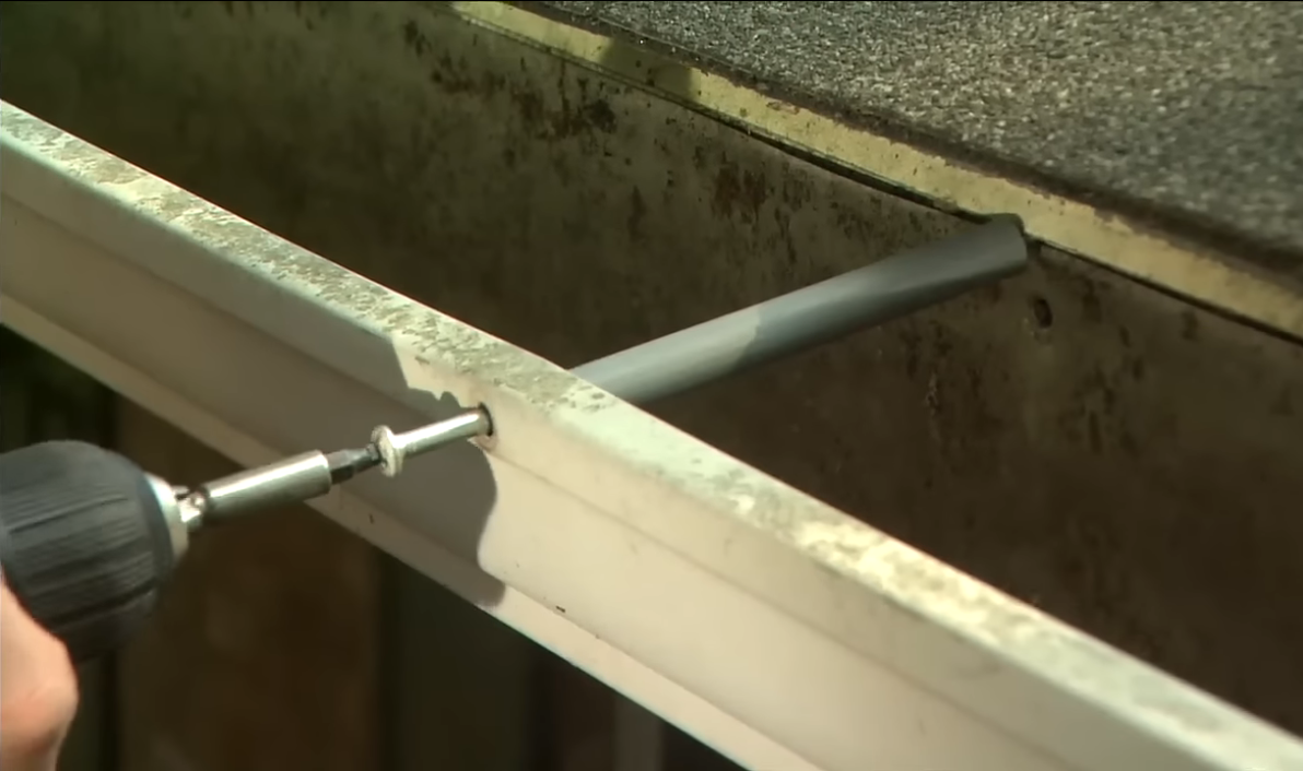 Drill used to screw gutter in place to repair damaged gutter