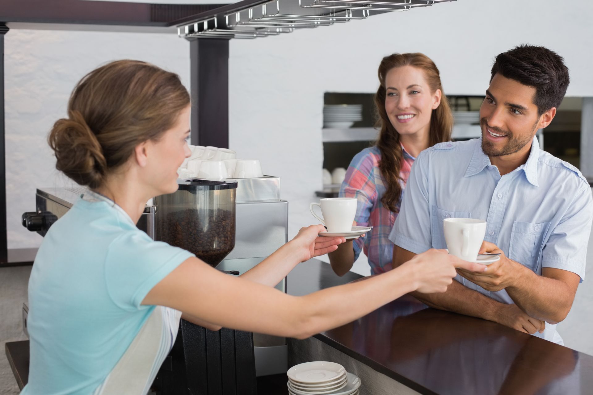 a woman is serving coffee to a man and a woman in a restaurant .