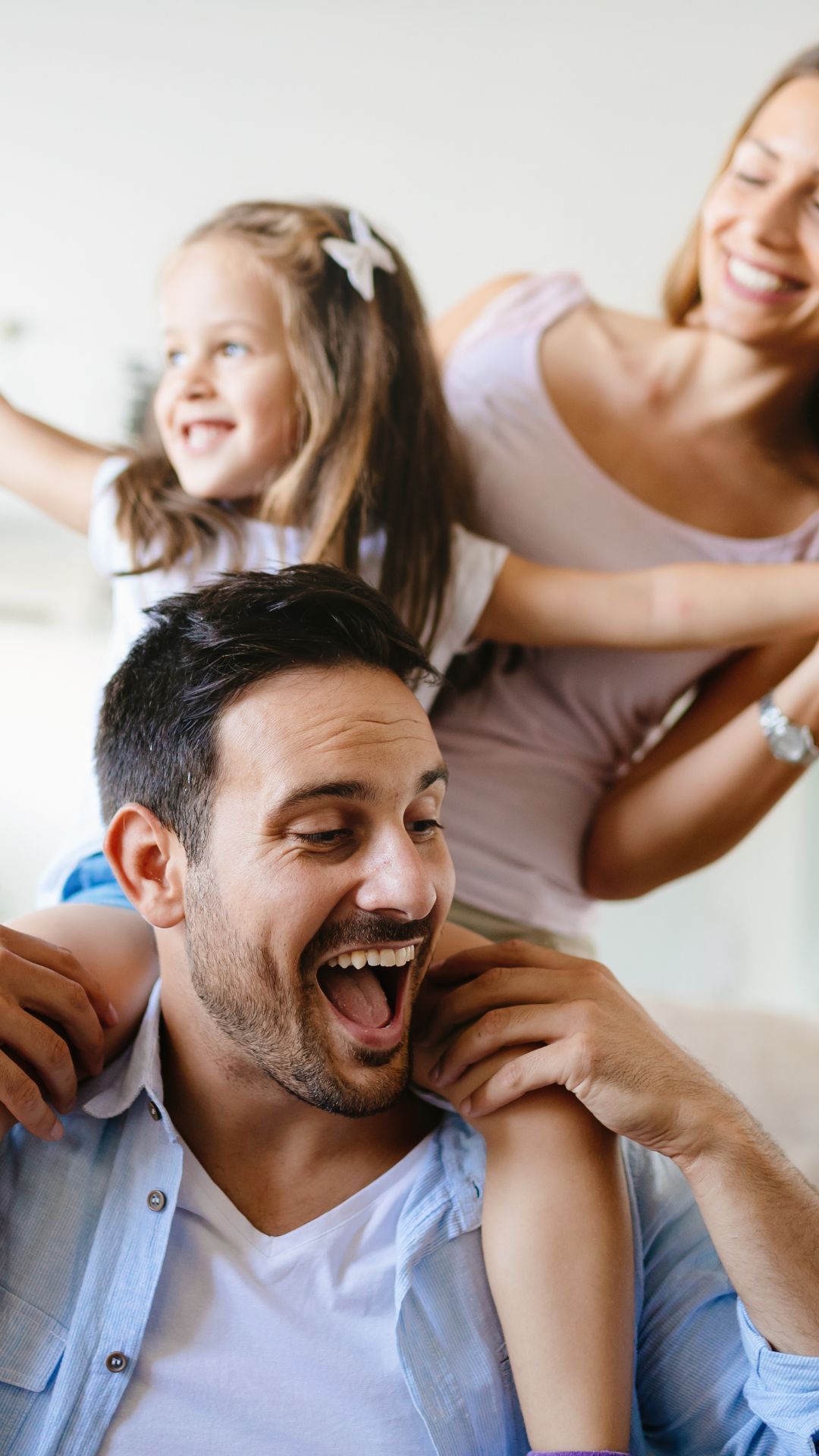 A man is carrying a little girl on his shoulders.