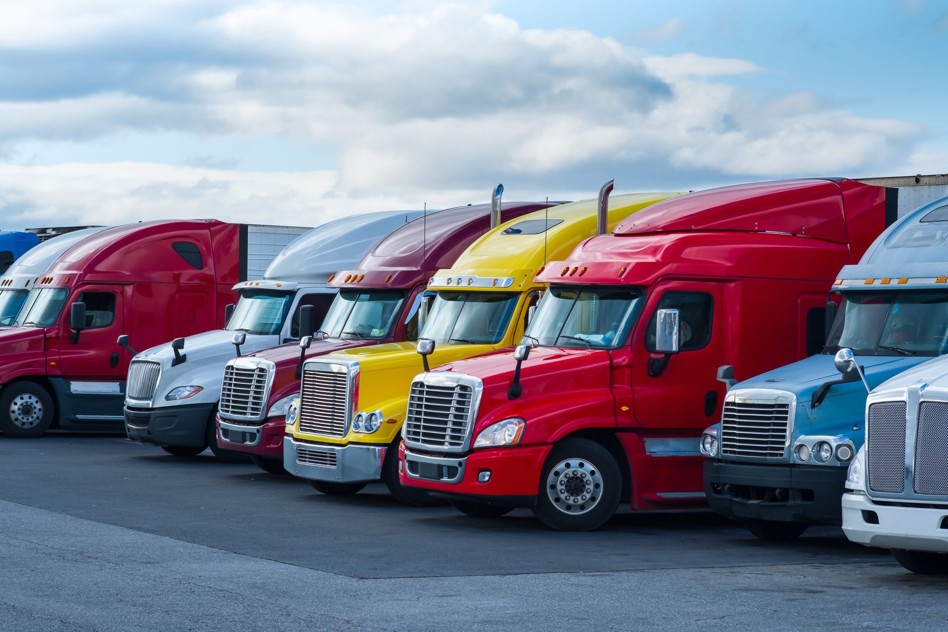 A row of semi trucks are parked in a parking lot.