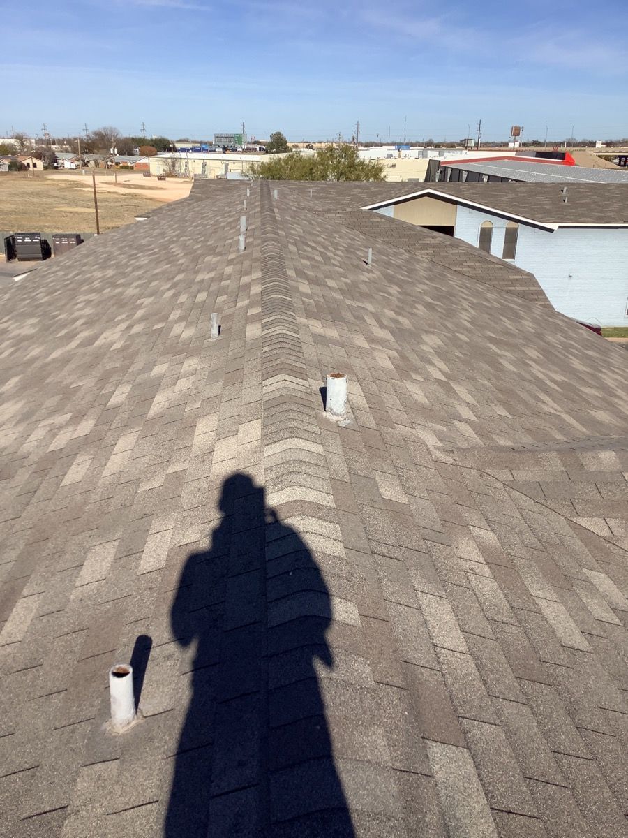 a shadow of a person is cast on the roof of a building The Amish Roofer.