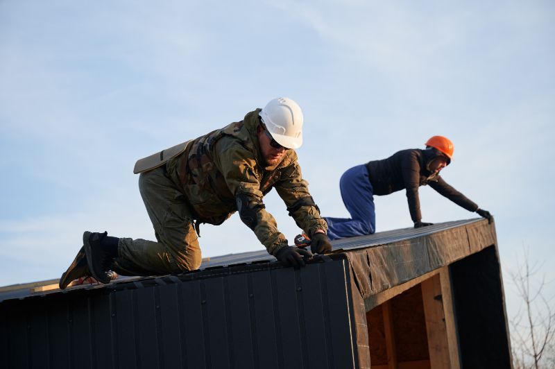 a man and a woman are working on the roof of a building The Amish Roofer.