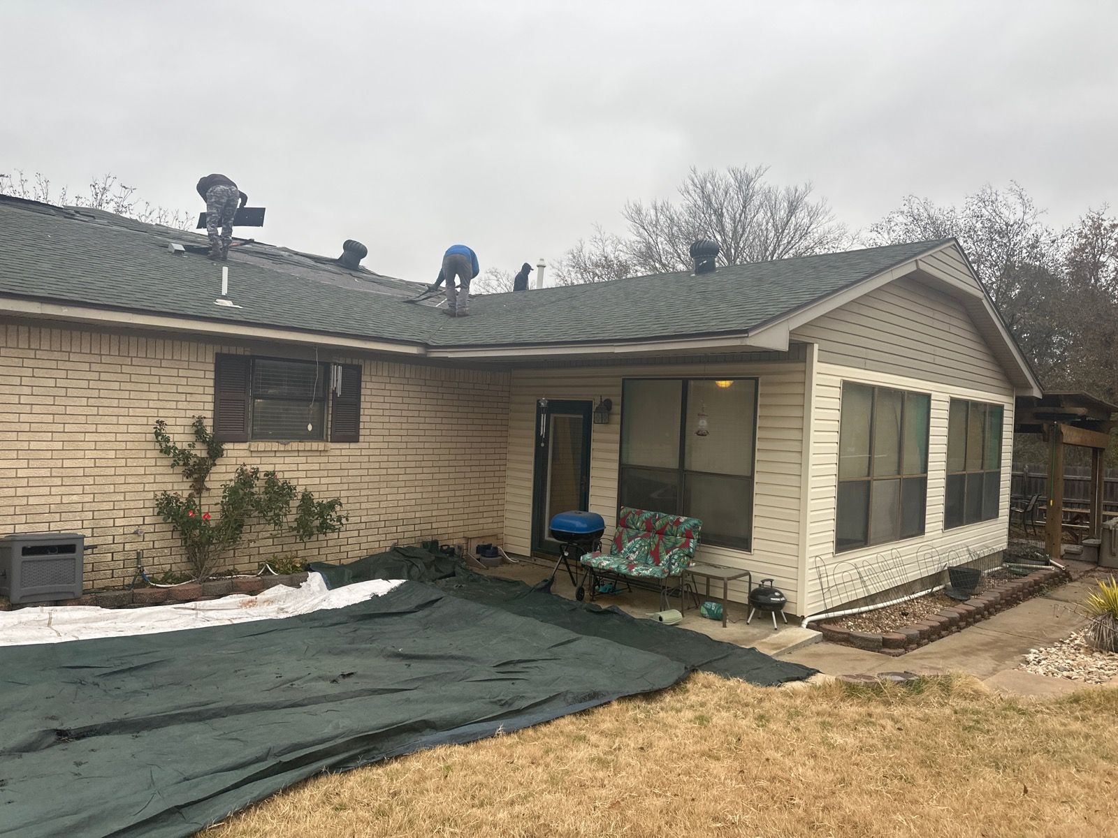 a house with a green tarp on the ground in front of it roof repair The Amish Roofer (940) 278-8299