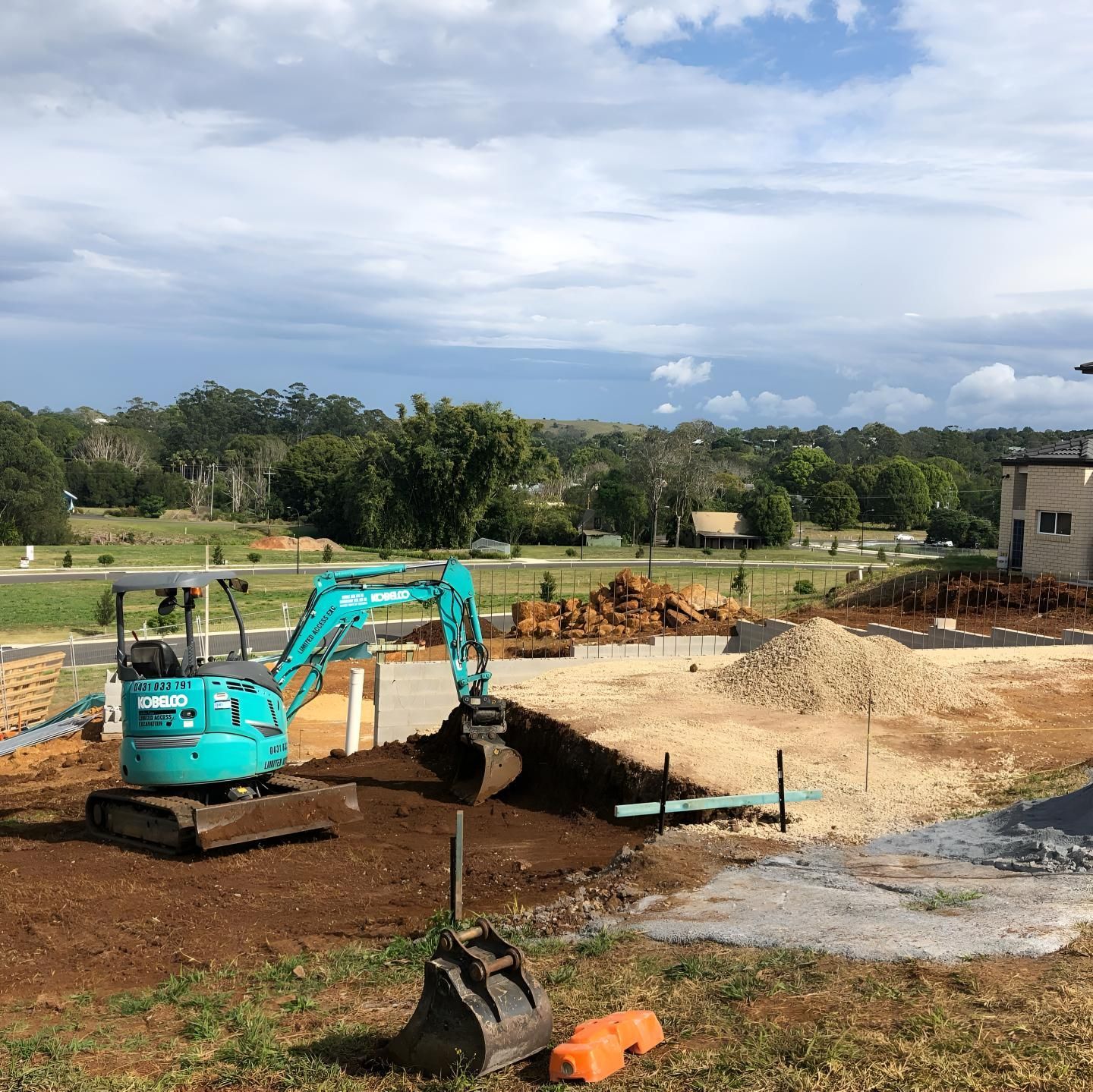 A Blue Excavator is Digging a Hole in the Ground — Limited Access Excavation In Evans Head, NSW