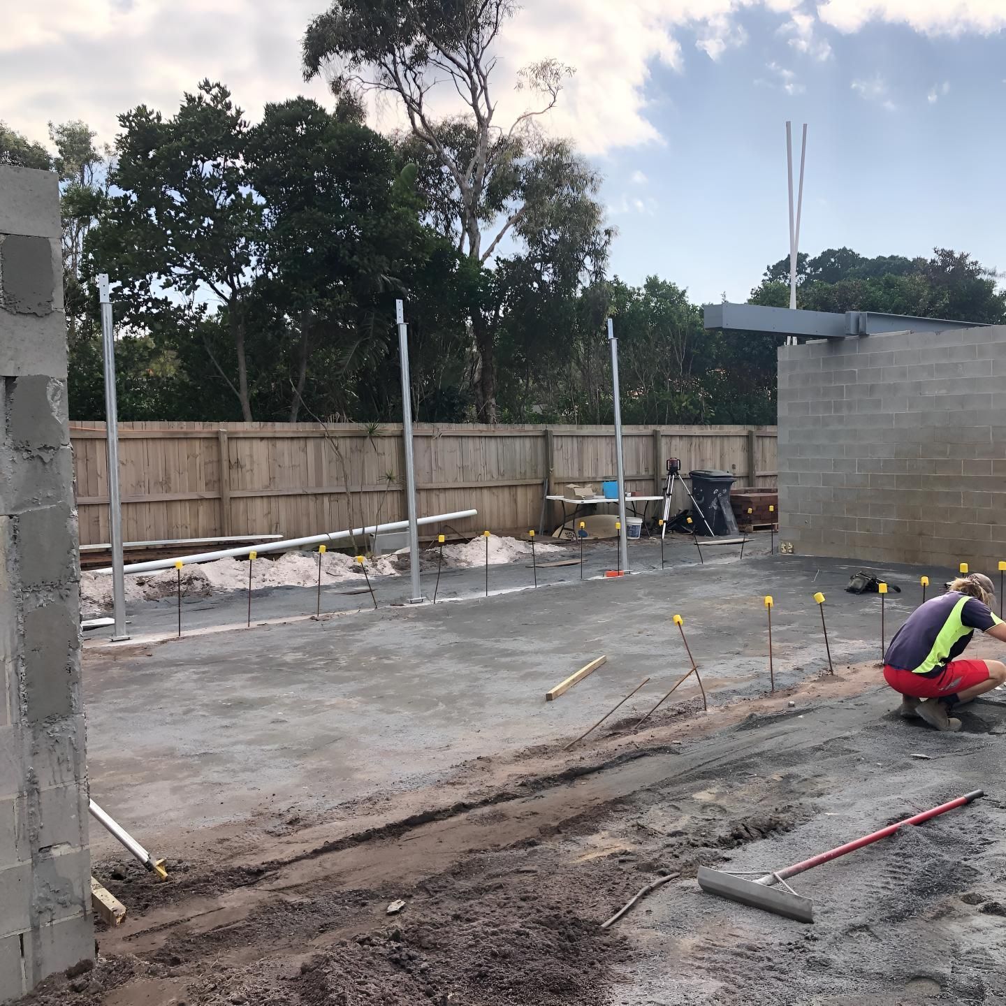A Man is Kneeling on a Concrete Surface in Front of a Fence — Limited Access Excavation In Pottsville, NSW