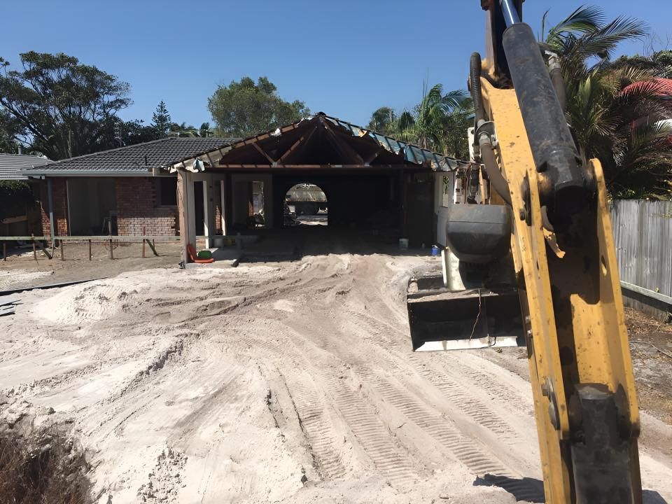 A Large Yellow Excavator is in Front of a House Under Construction — Limited Access Excavation In Suffolk Park, NSW