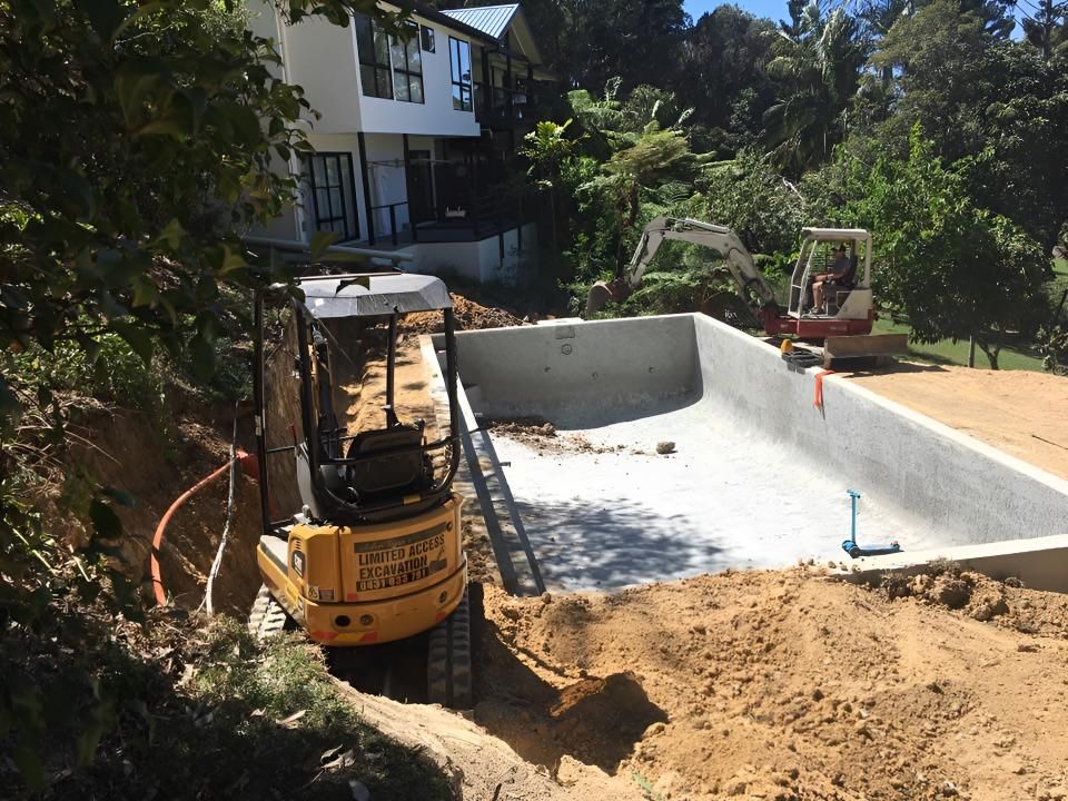 A Yellow Excavator is Working on a Swimming Pool in Front of a House — Limited Access Excavation In Suffolk Park, NSW