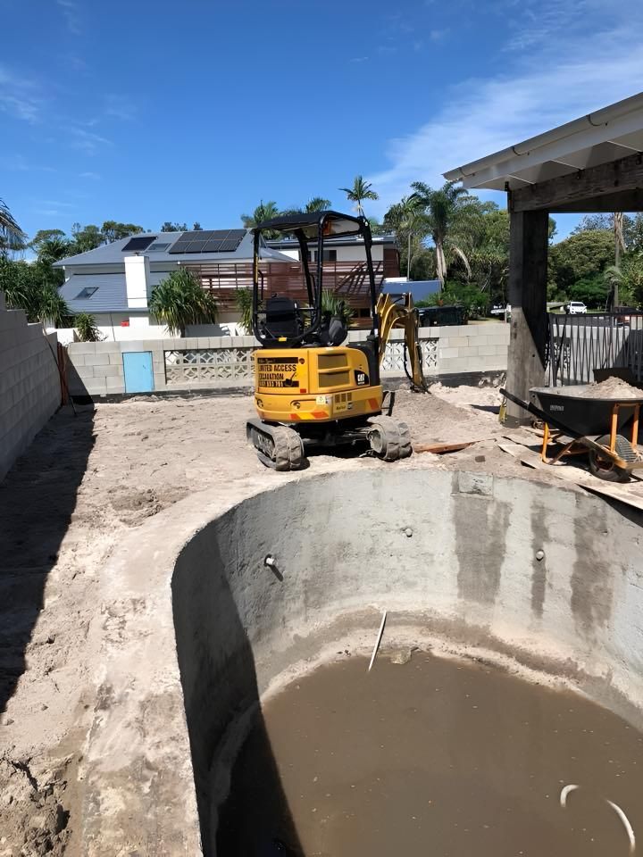 A Yellow Excavator is Sitting in the Dirt Next to a Pool — Limited Access Excavation In Suffolk Park, NSW