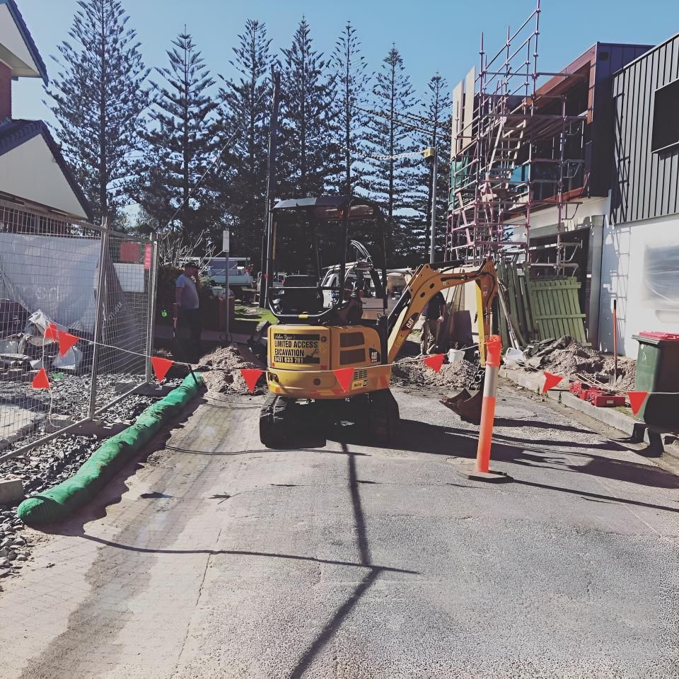 A Yellow Excavator is Driving Down a Street — Limited Access Excavation In Tweed Heads, NSW