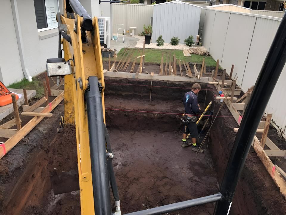 A Man is Standing in a Hole in the Ground Next to a Crane — Limited Access Excavation In Alstonville, NSW