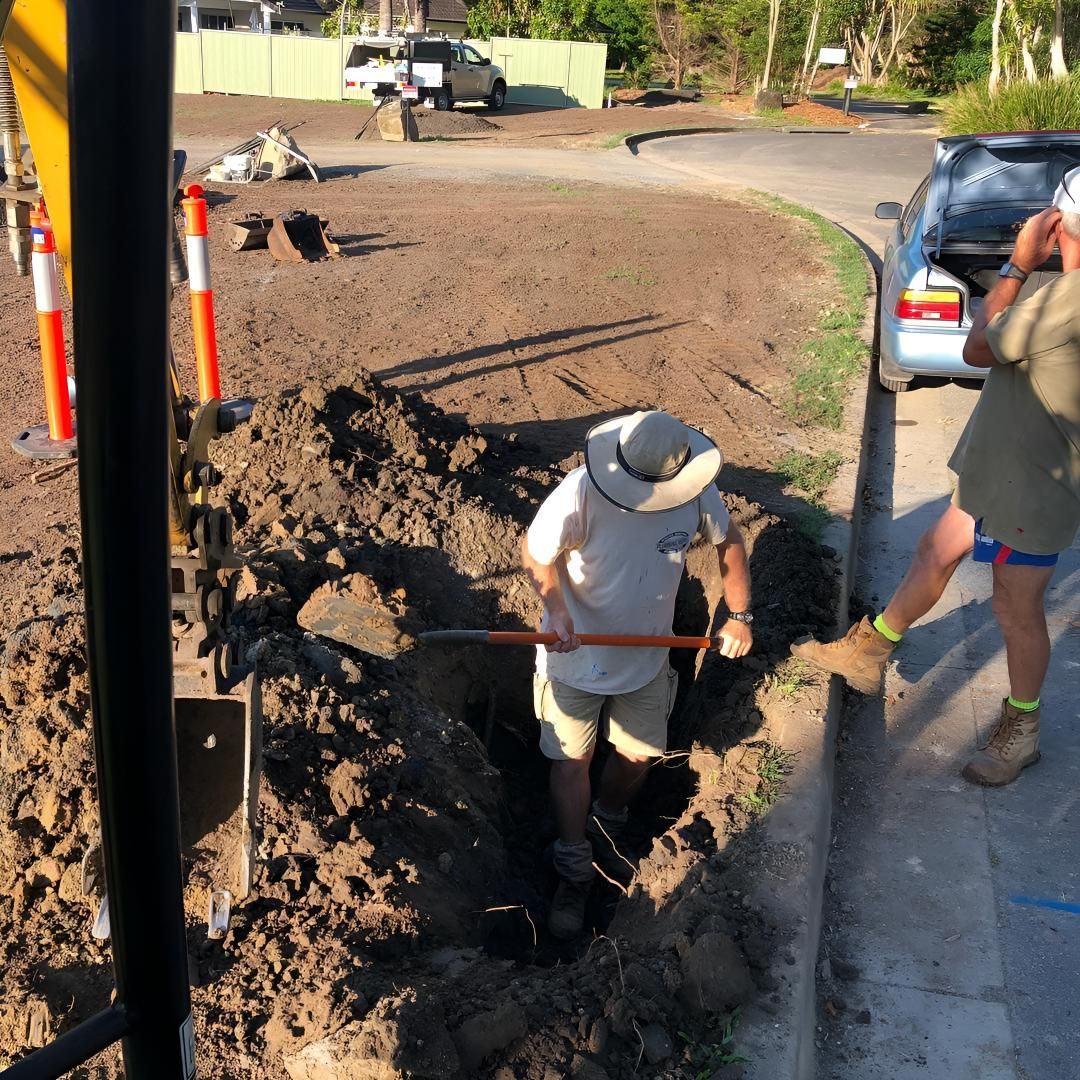 A Man in a Hat is Digging in the Dirt With a Shovel — Limited Access Excavation In Pottsville, NSW