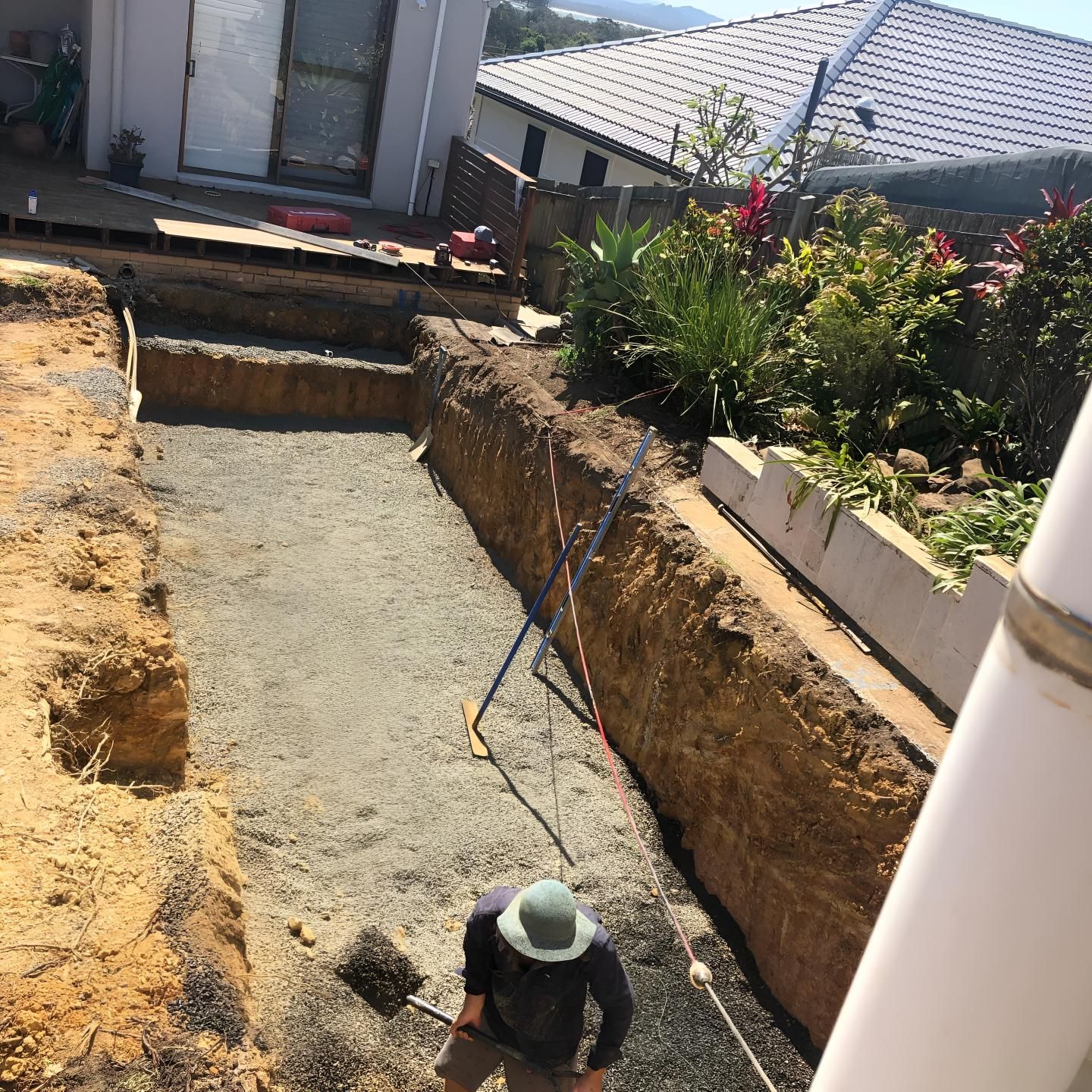 A Man Wearing a Hat is Digging in the Dirt Near a House — Limited Access Excavation In Evans Head, NSW