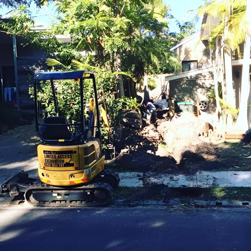 A Small Yellow Excavator is Parked on the Side of the Road — Limited Access Excavation In Tweed Heads, NSW