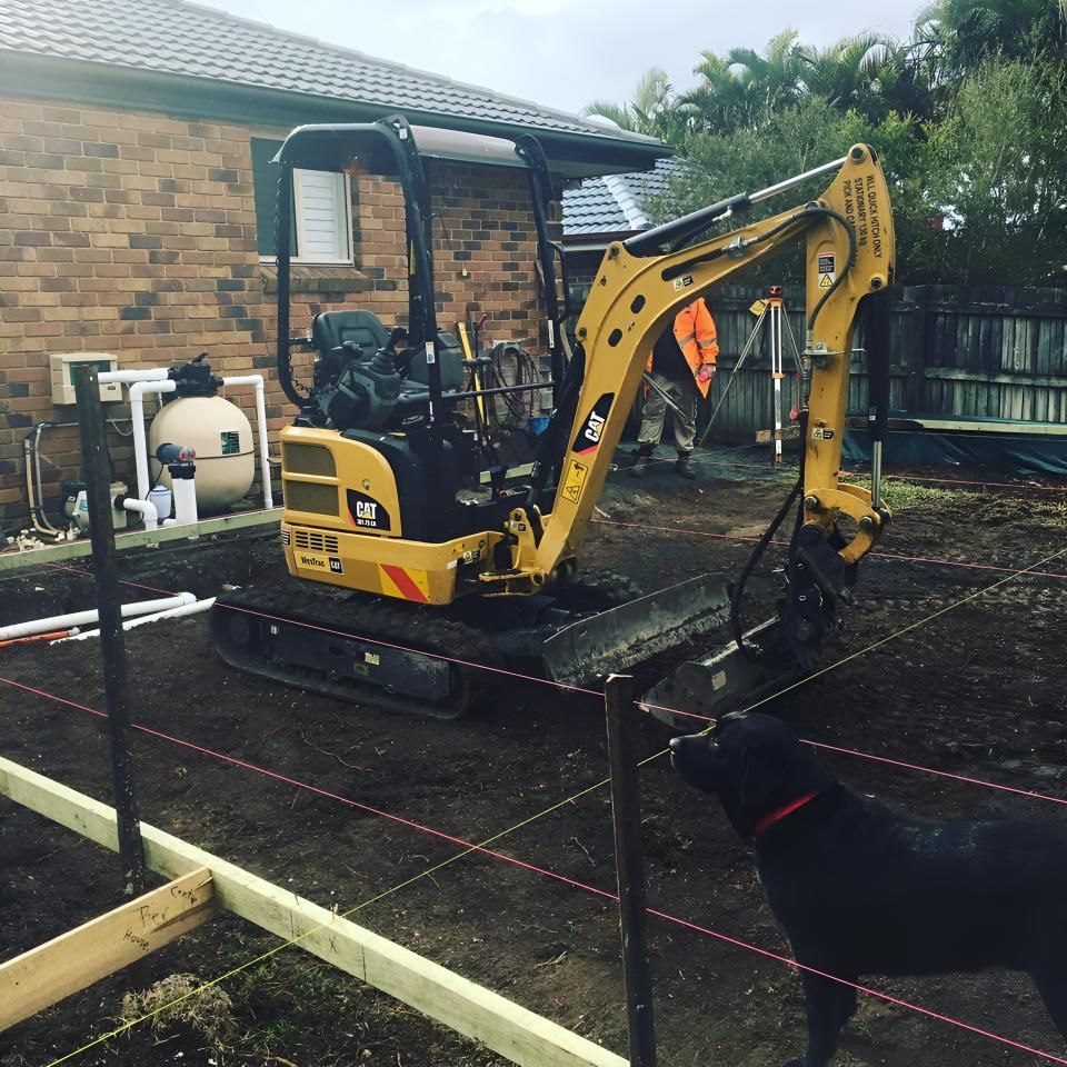 A Cat Excavator is Parked in Front of a Brick House — Limited Access Excavation In Murwillumbah, NSW