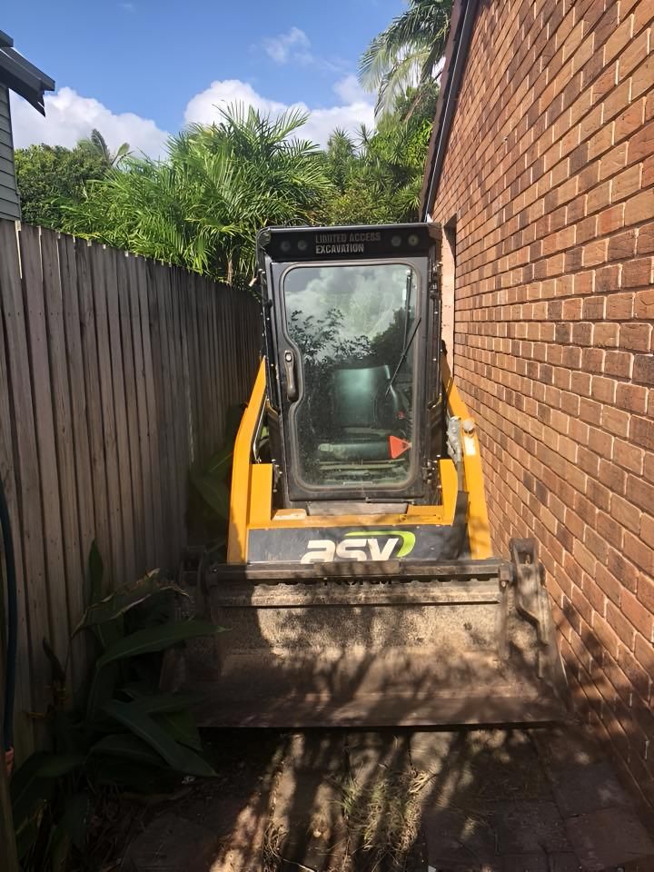 A Bulldozer is Parked in a Backyard Next to a Brick Wall — Limited Access Excavation In Suffolk Park, NSW