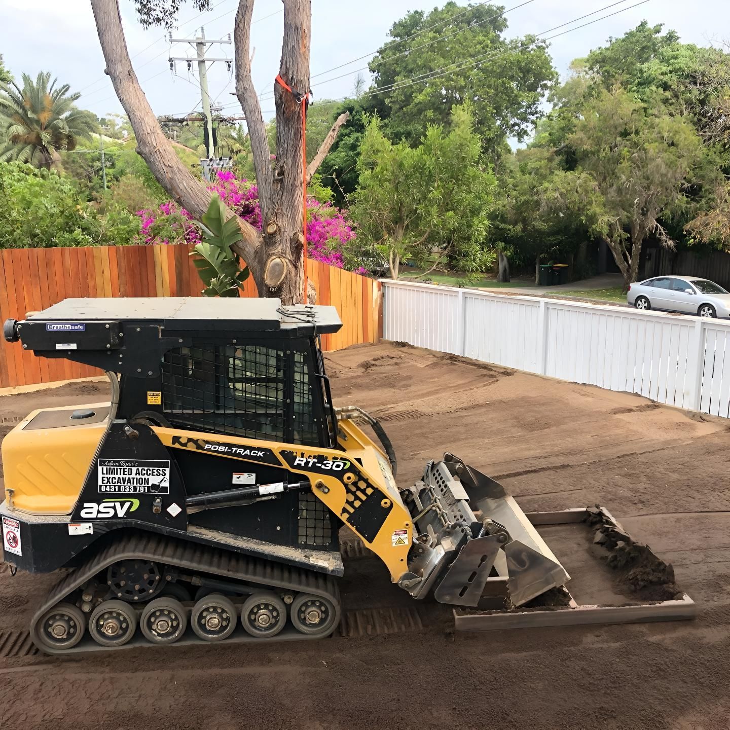A Yellow and Black Bulldozer is Sitting in the Dirt in Front of a Fence — Limited Access Excavation In Suffolk Park, NSW