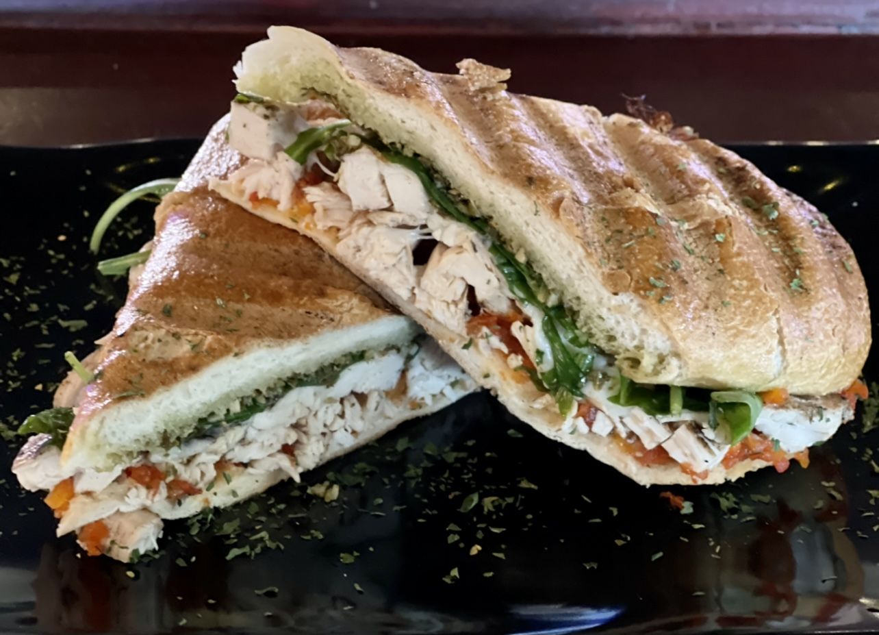 A sandwich is cut in half on a black plate.