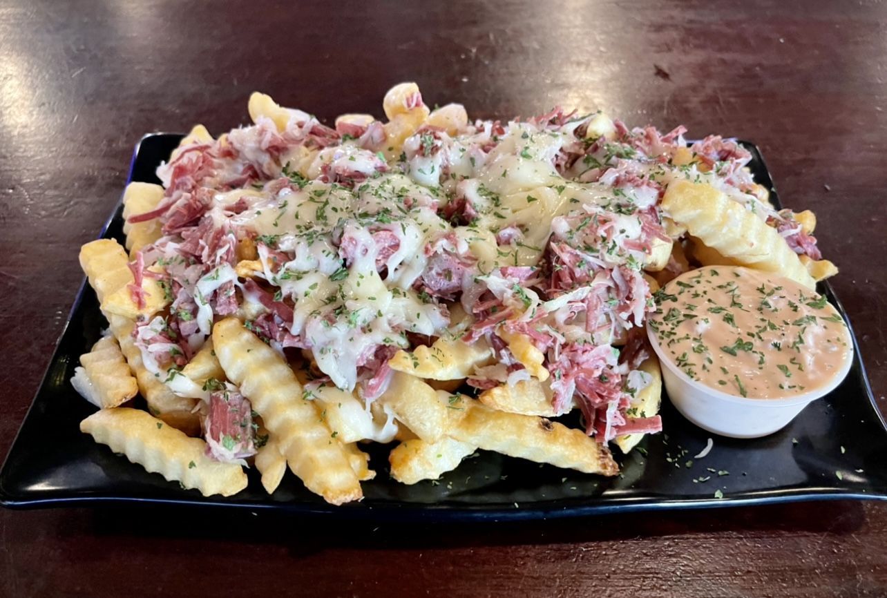 A black plate topped with french fries and a dipping sauce.