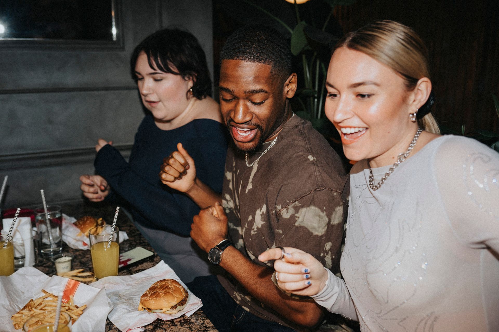 A group of people are sitting at a table eating hamburgers and french fries.