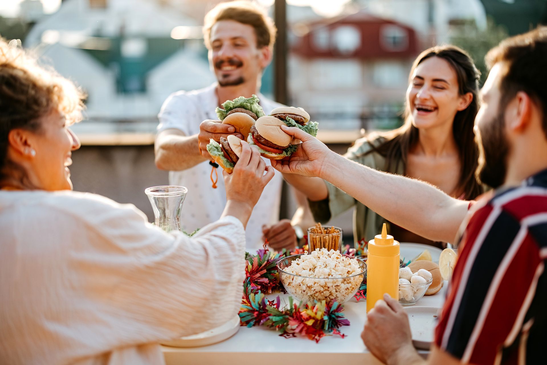 A group of people are sitting at a table eating hamburgers and popcorn.