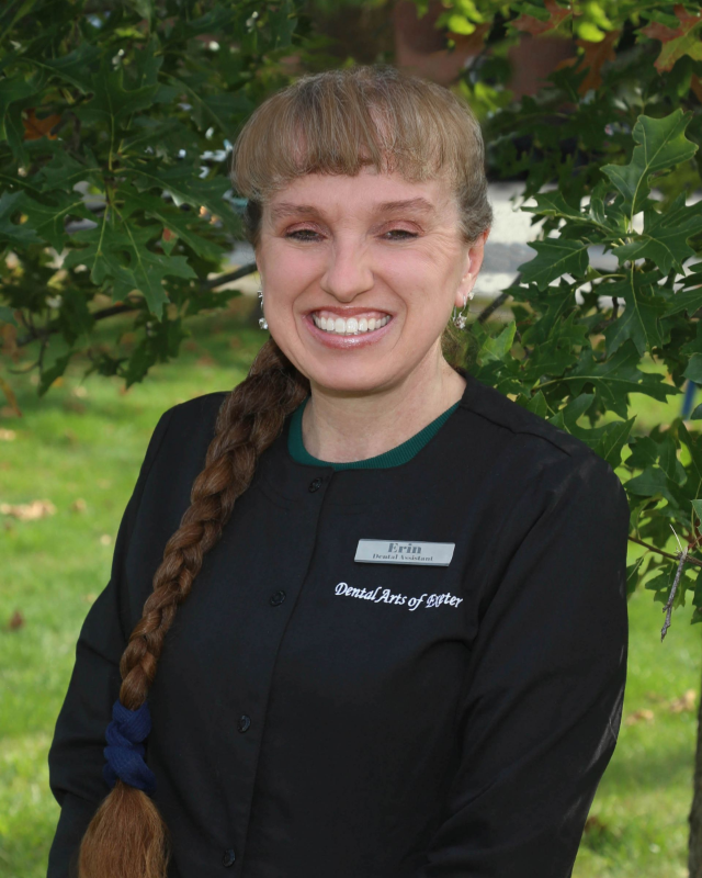 Smiling woman with long braid in black uniform outdoors.