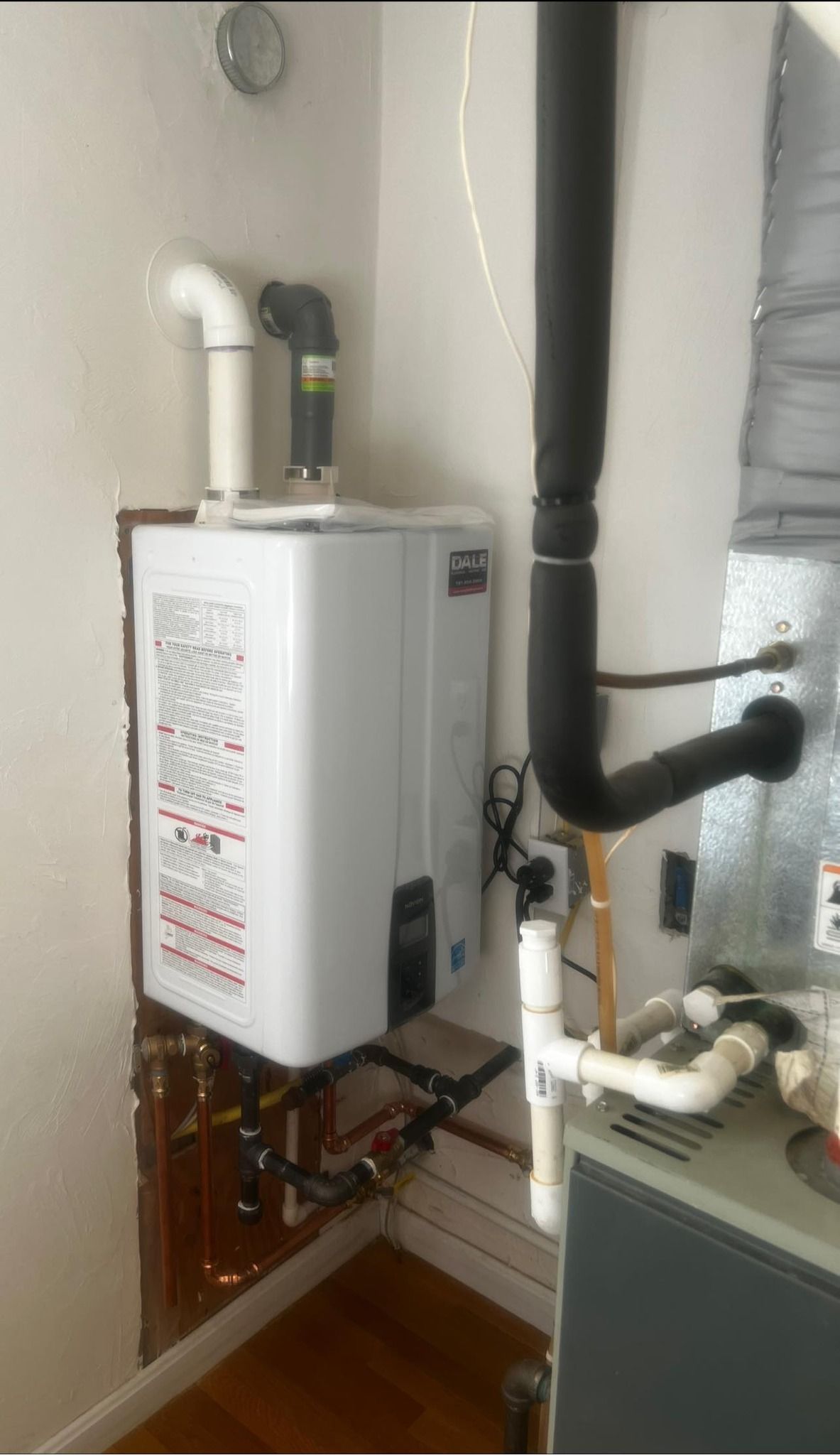 a water heater is mounted to the wall next to a furnace .