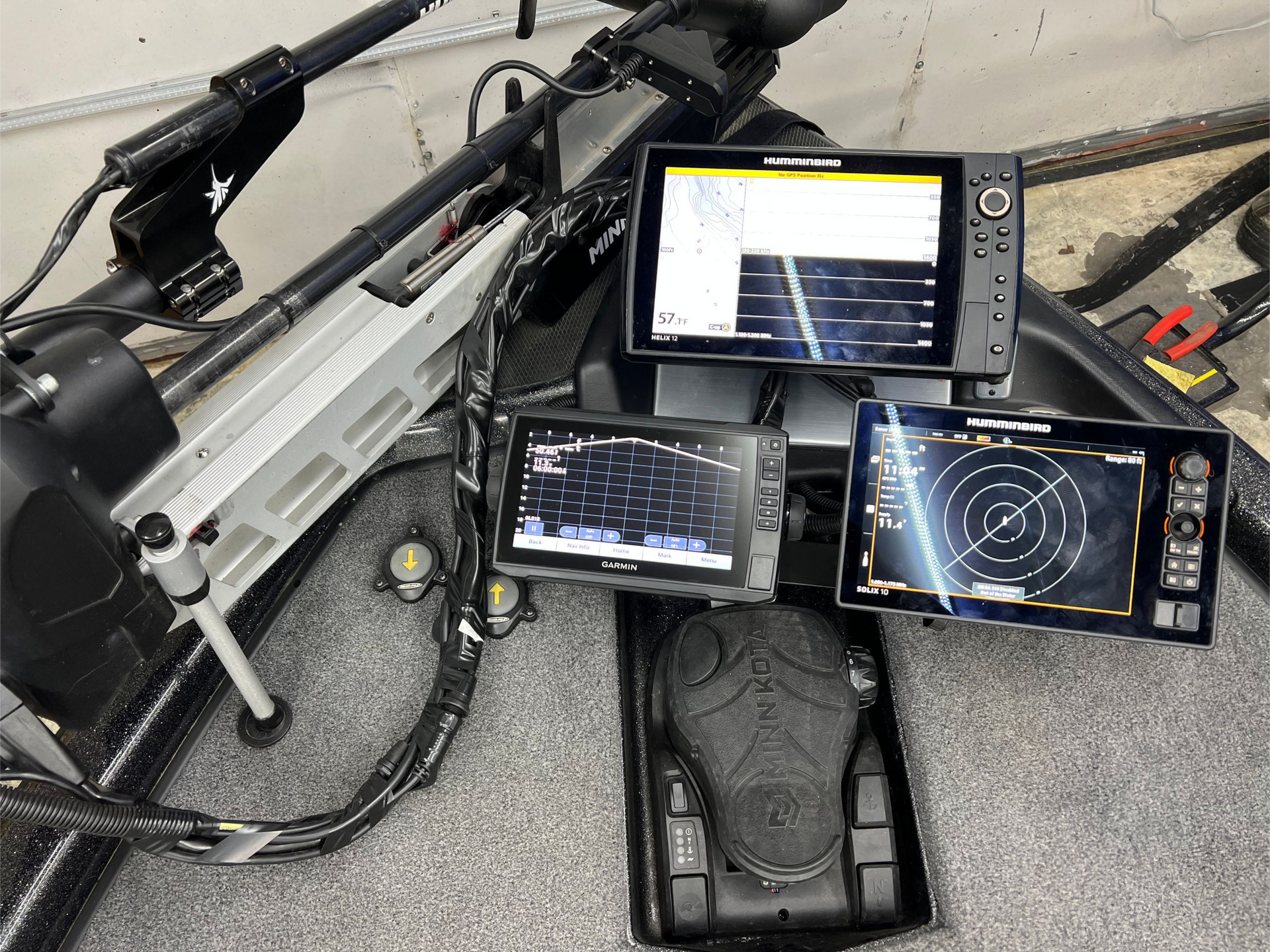 Fishing boat console with three sonar screens, foot pedal, and trolling motor.