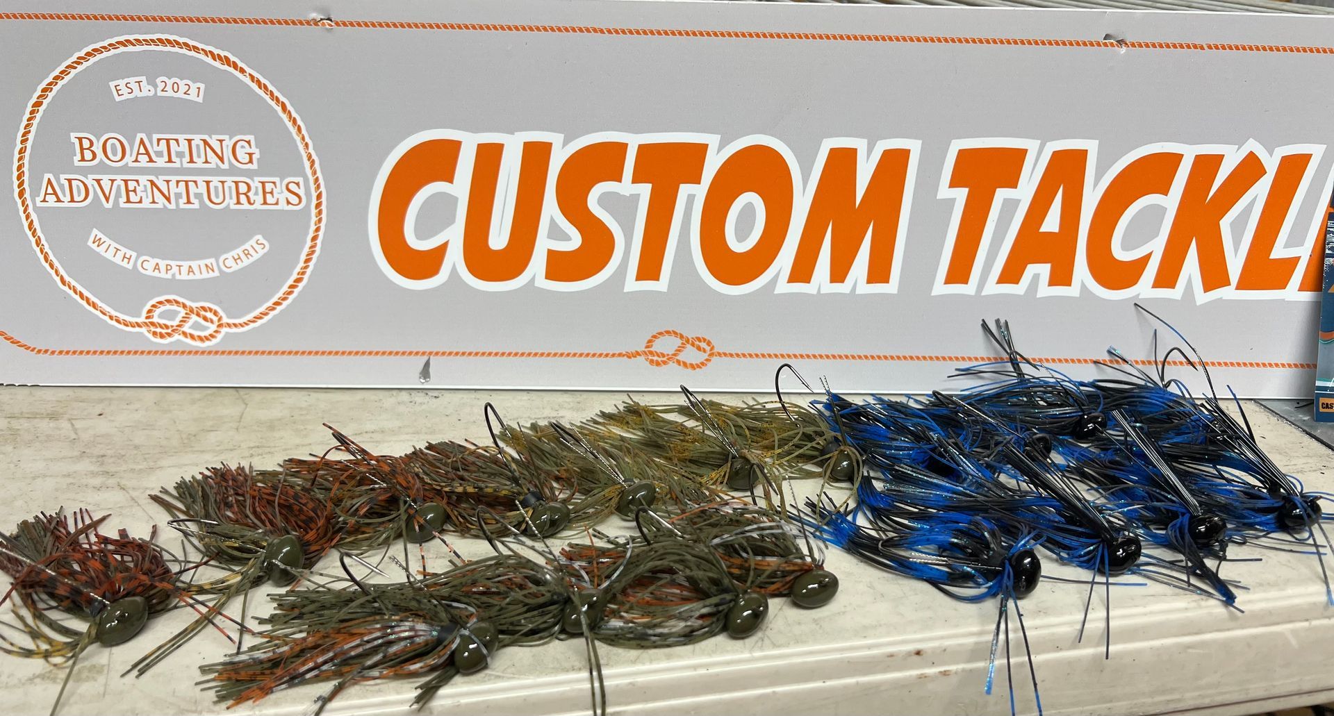 Rows of custom fishing lures in brown, green, and blue, displayed under 