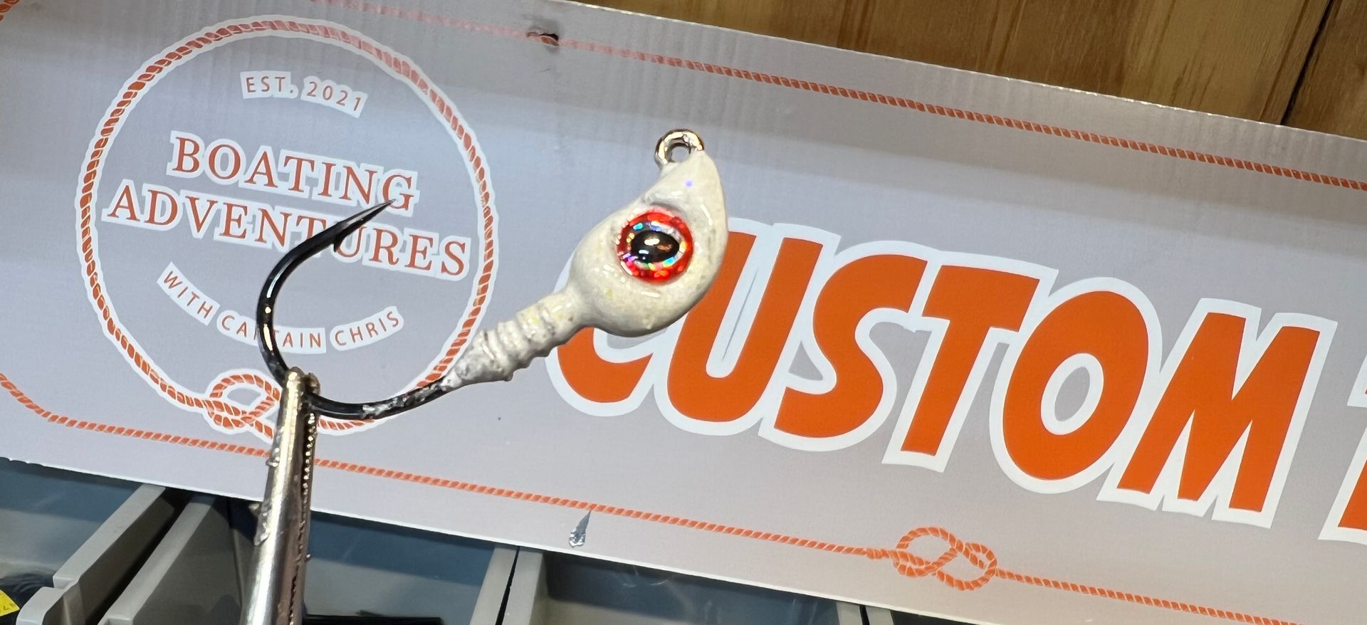 Rows of custom fishing lures in brown, green, and blue, displayed under 