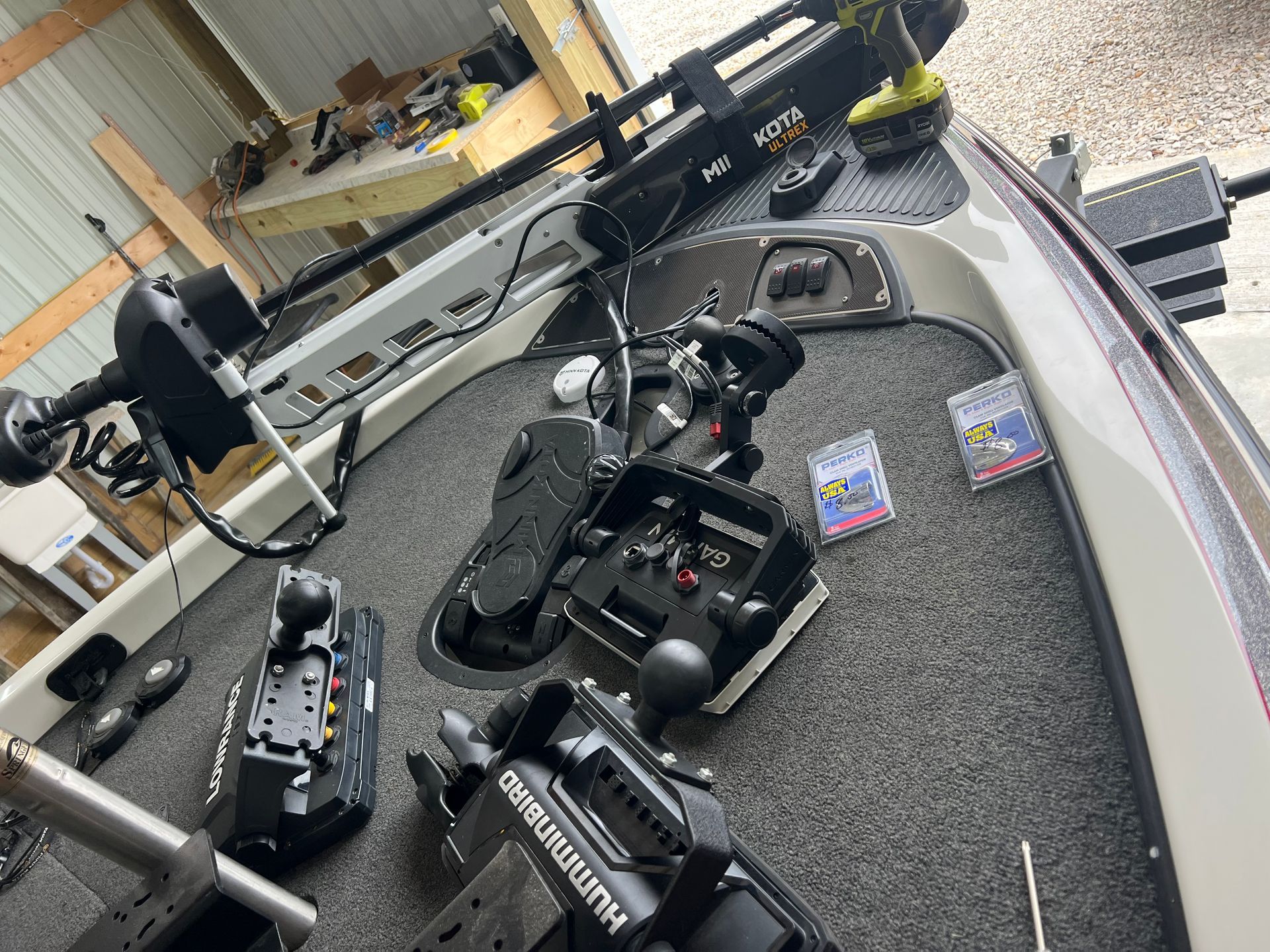 A boat deck with fishing equipment, including a trolling motor and control pedals.