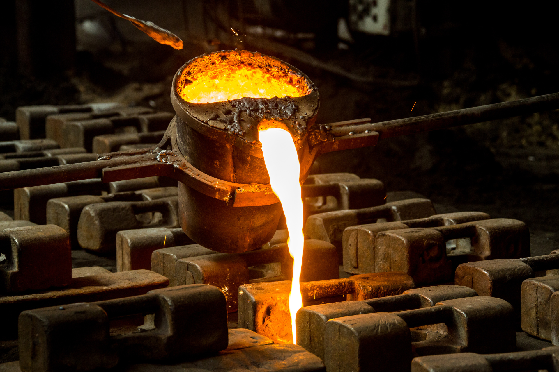 Molten metal pouring from a crucible into molds in a foundry.
