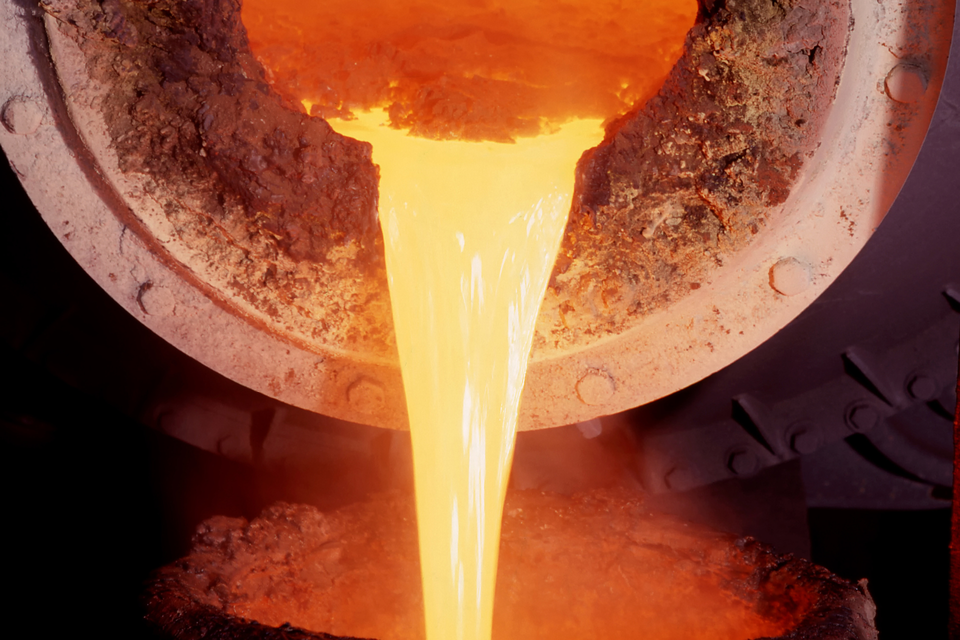 Molten orange metal pouring from a crucible into a mold.