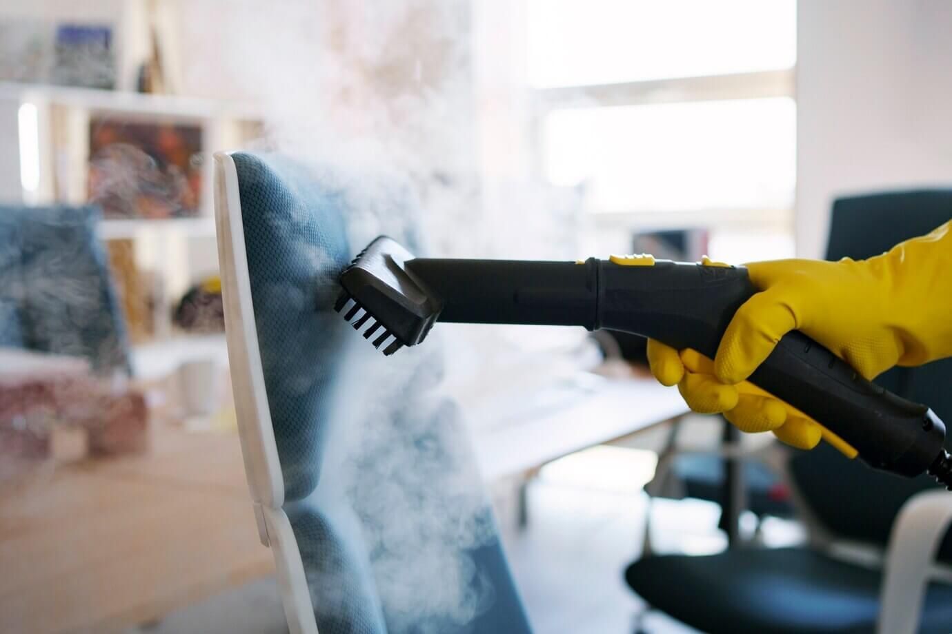 Una persona está limpiando una silla con un limpiador a vapor.