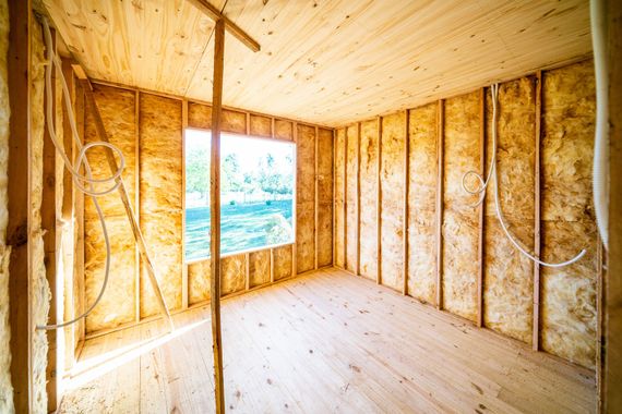 Interior of a room under construction, with wooden studs and exposed insulation. 