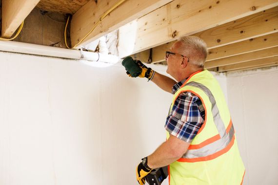 Person in safety vest inspecting ceiling. 