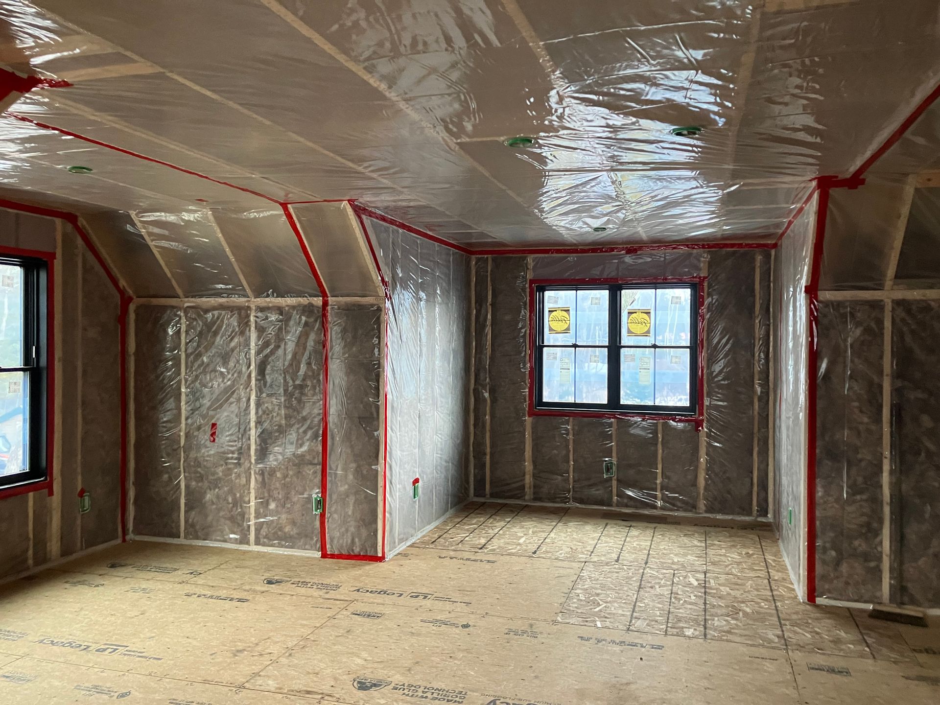 Person installing insulation in a building's walls and ceiling. 