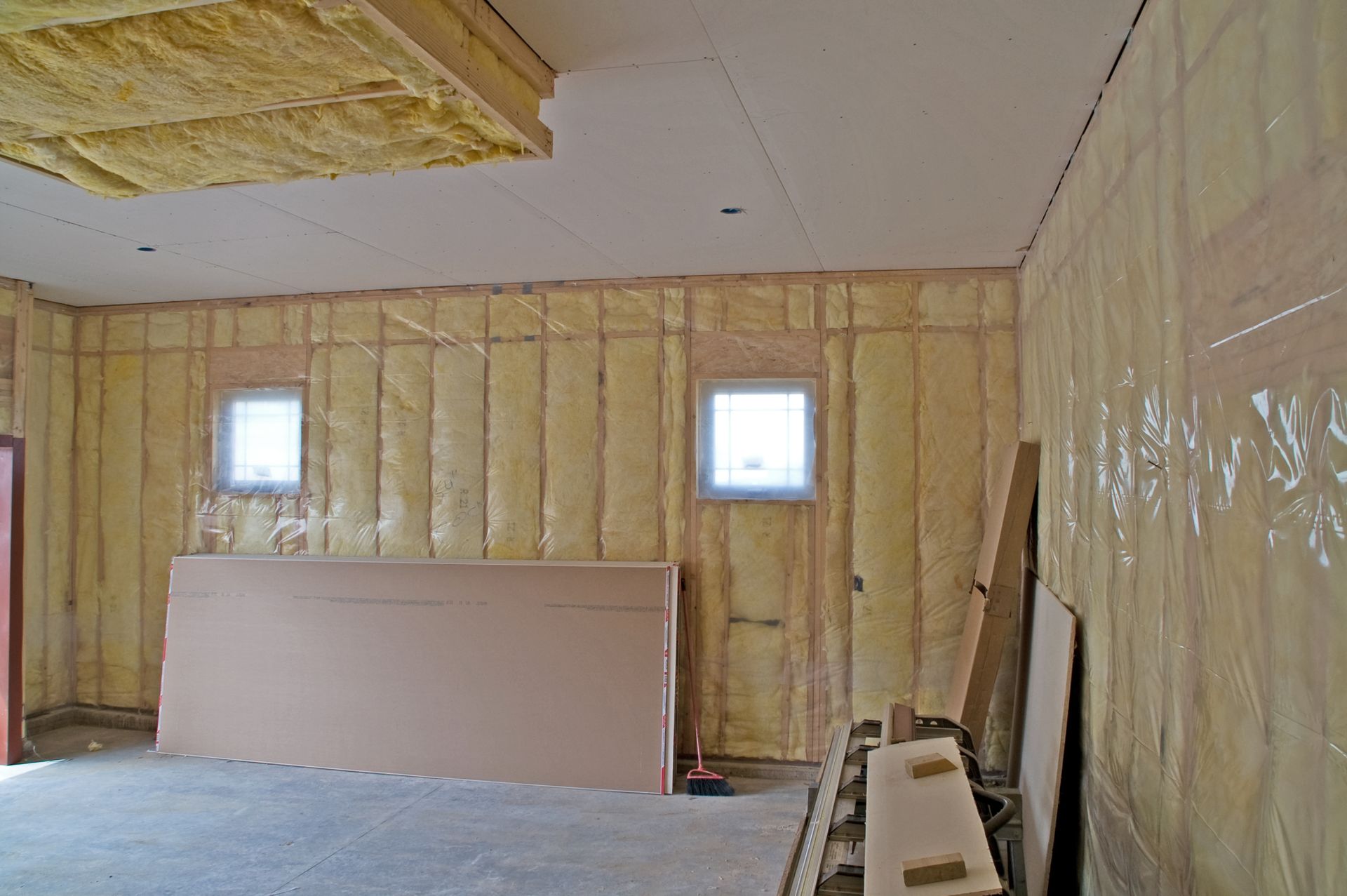 Interior of a room under construction, with exposed insulation in walls and ceiling.