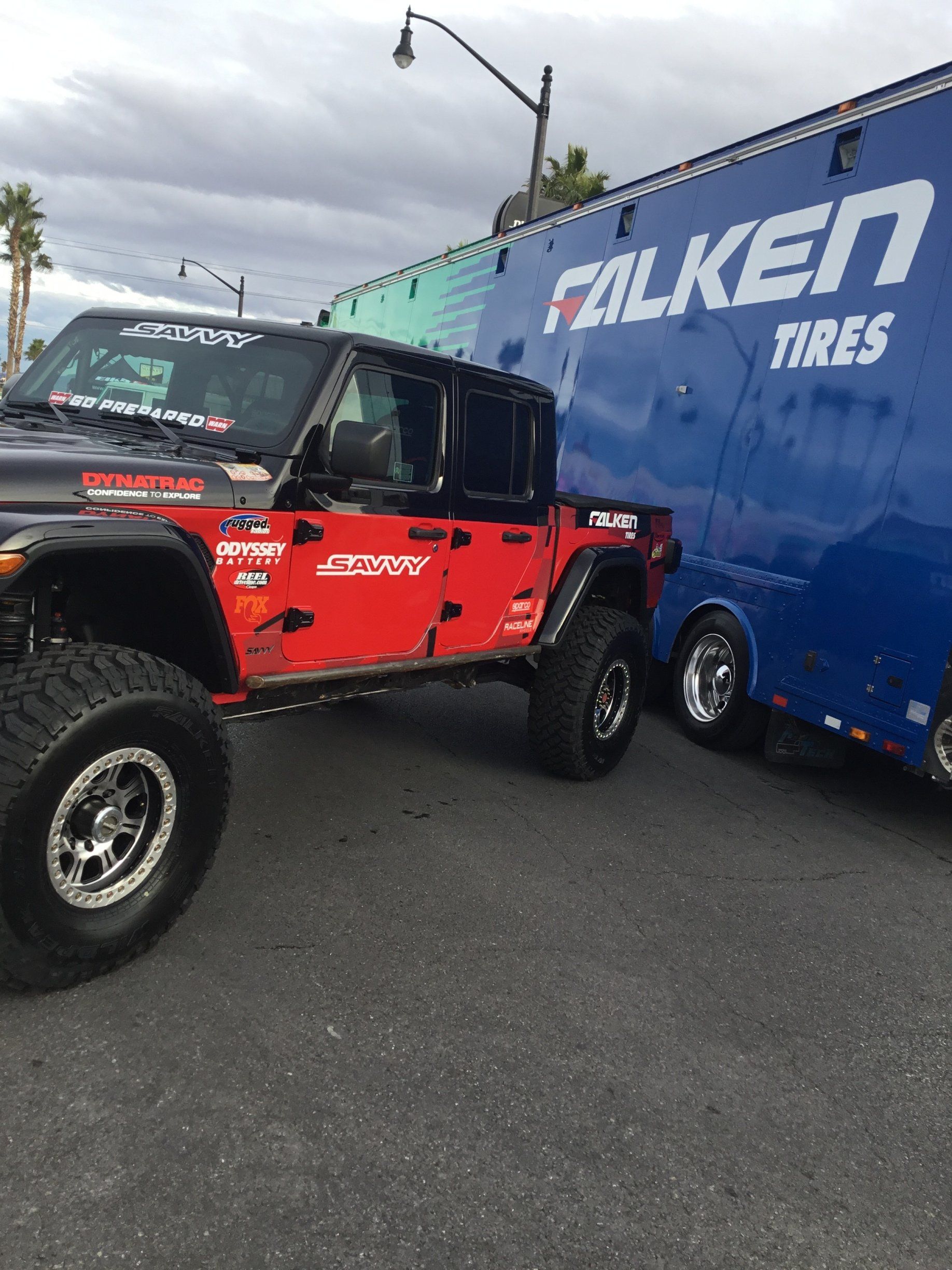 A red jeep is parked next to a blue trailer that says falken tires