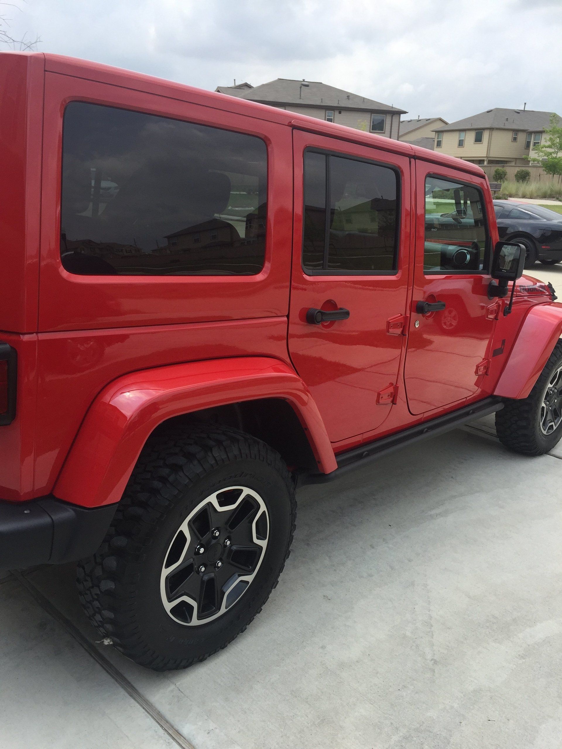 A red jeep is parked on the side of the road