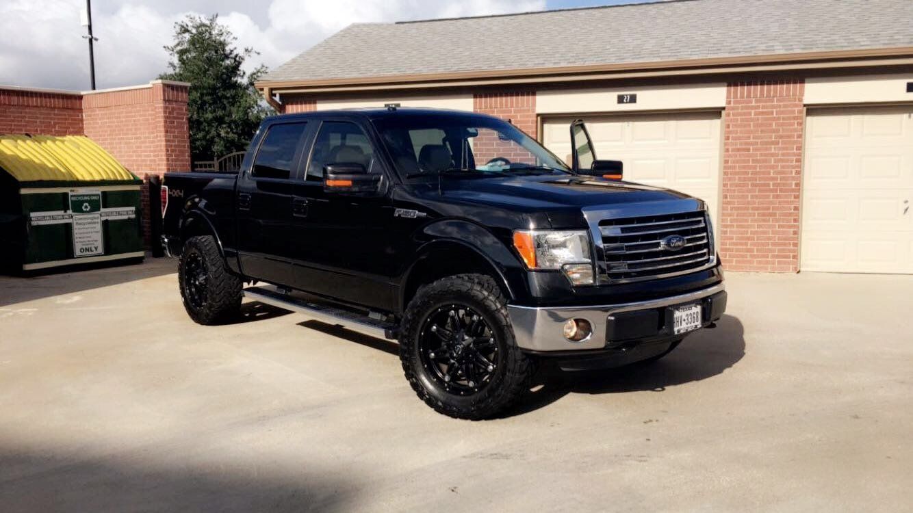 A black pickup truck is parked in front of a garage.
